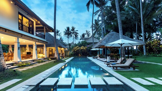 A poolside area with a clear view of the pool, lounge chairs, and a thatched-roof structure. - Beautiful Private Pool Villa by the Beach in Candidasa (Manggis)