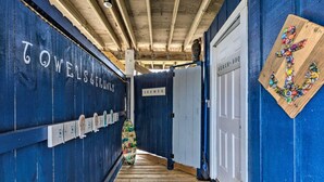 A hallway with blue walls, a wooden floor, and a sign reading "TOWELS & TUBES". - The Blue Pearl · Experience Coastal Living at Blue Pearl: Private Beach Access (Gulf Shores)