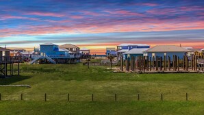 A coastal area with beach houses and wooden structures, likely a vacation rental or resort. - The Blue Pearl · Experience Coastal Living at Blue Pearl: Private Beach Access (Gulf Shores)