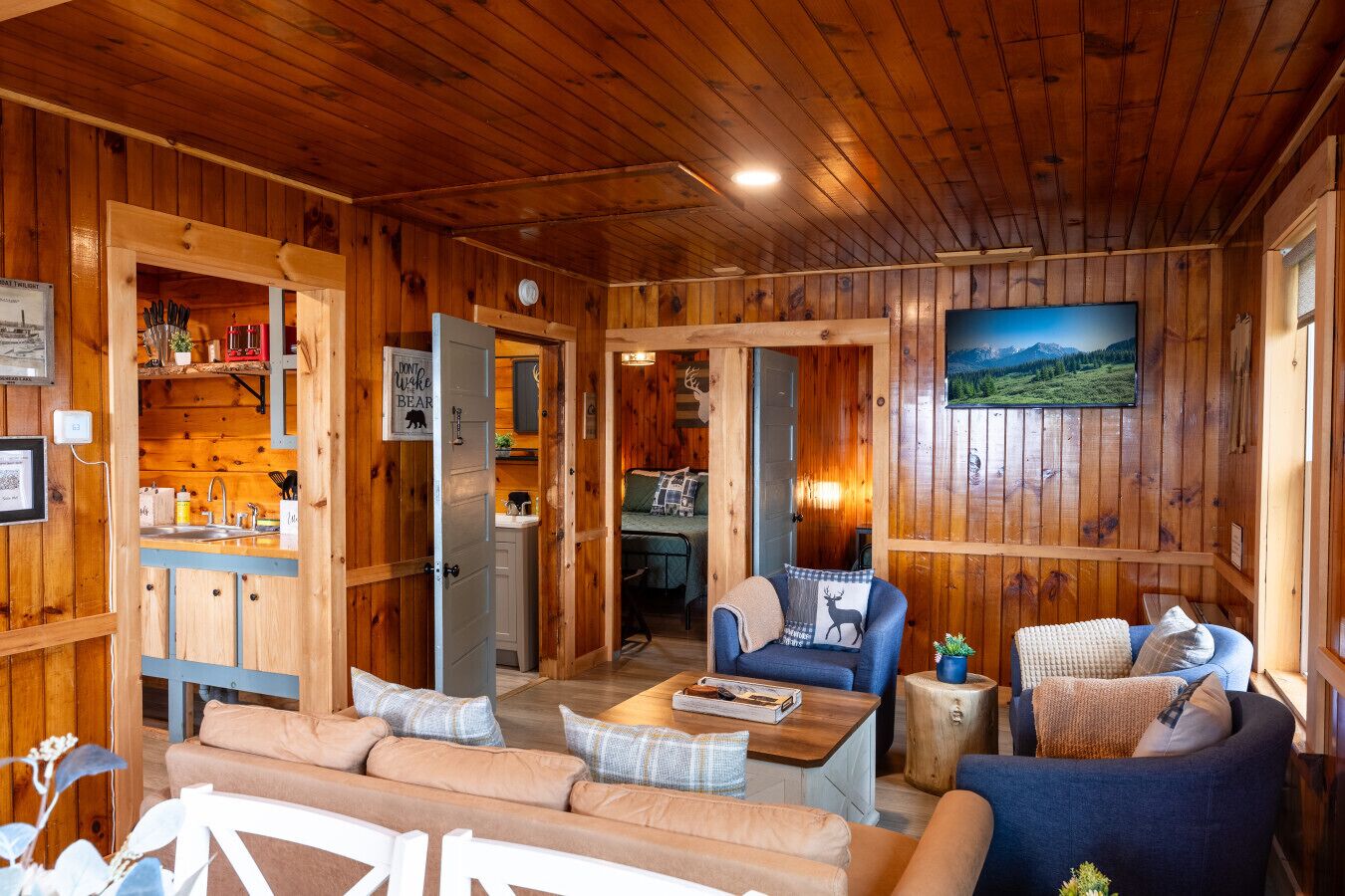 Un acogedor interior de cabaña con detalles de madera, un comedor y una sala de estar con sofá y sillones.