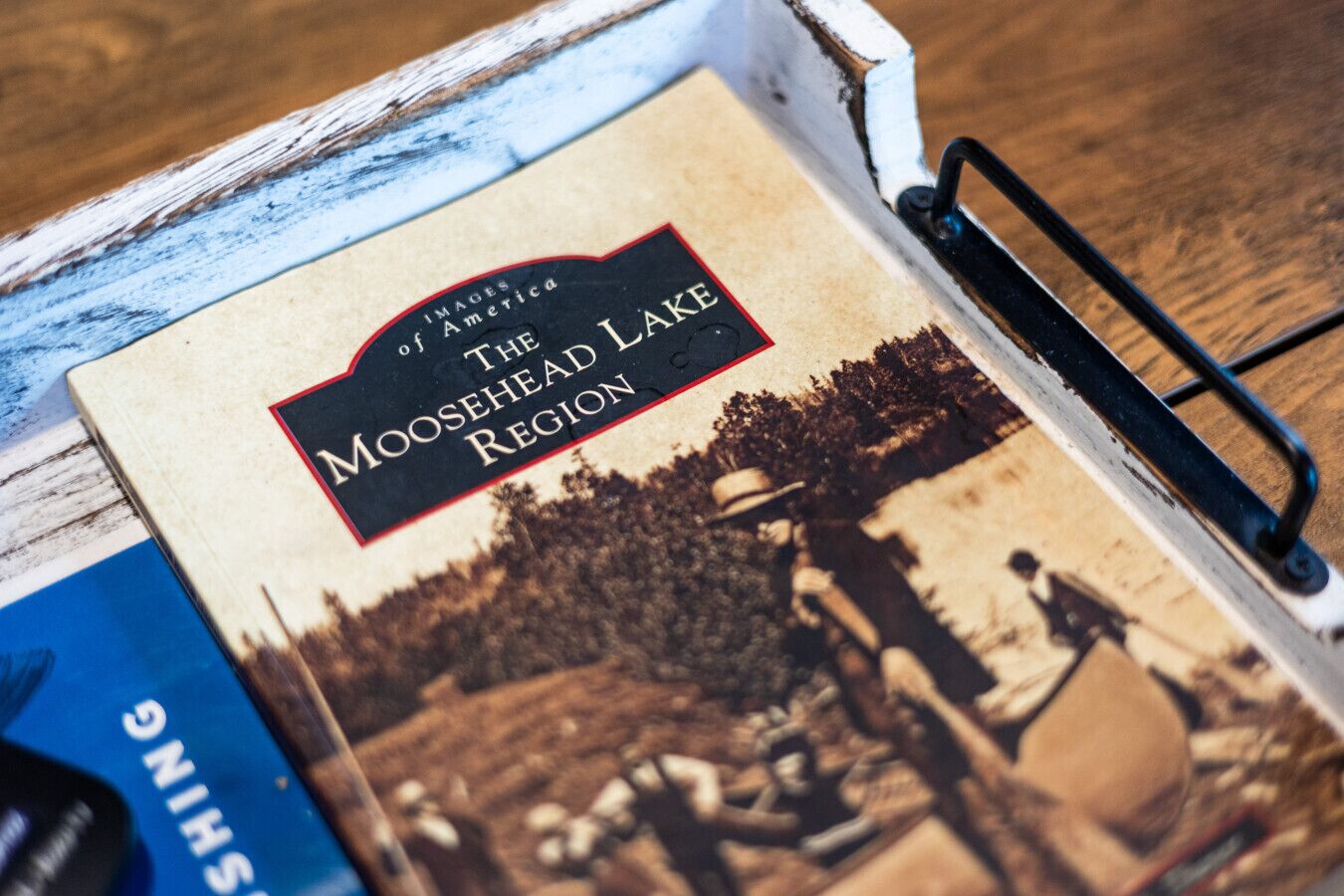 Kirjan nimi on ”Moosehead-järven alue”, siinä on musta kansi ja siinä on kuva järvimaisemasta.