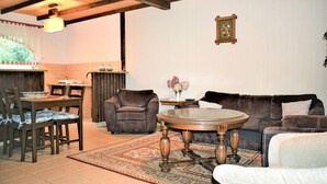 A cozy living room with a brown sofa, a round coffee table, and a dining area with a wooden table and chairs.