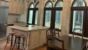 A kitchen with a central island, wooden chairs, and a chandelier. - Historic Maison du Roy/Royal Chambers -3BR/2BR Apartment with Royal Fireplace (Saint-Antonin-Noble-Val)