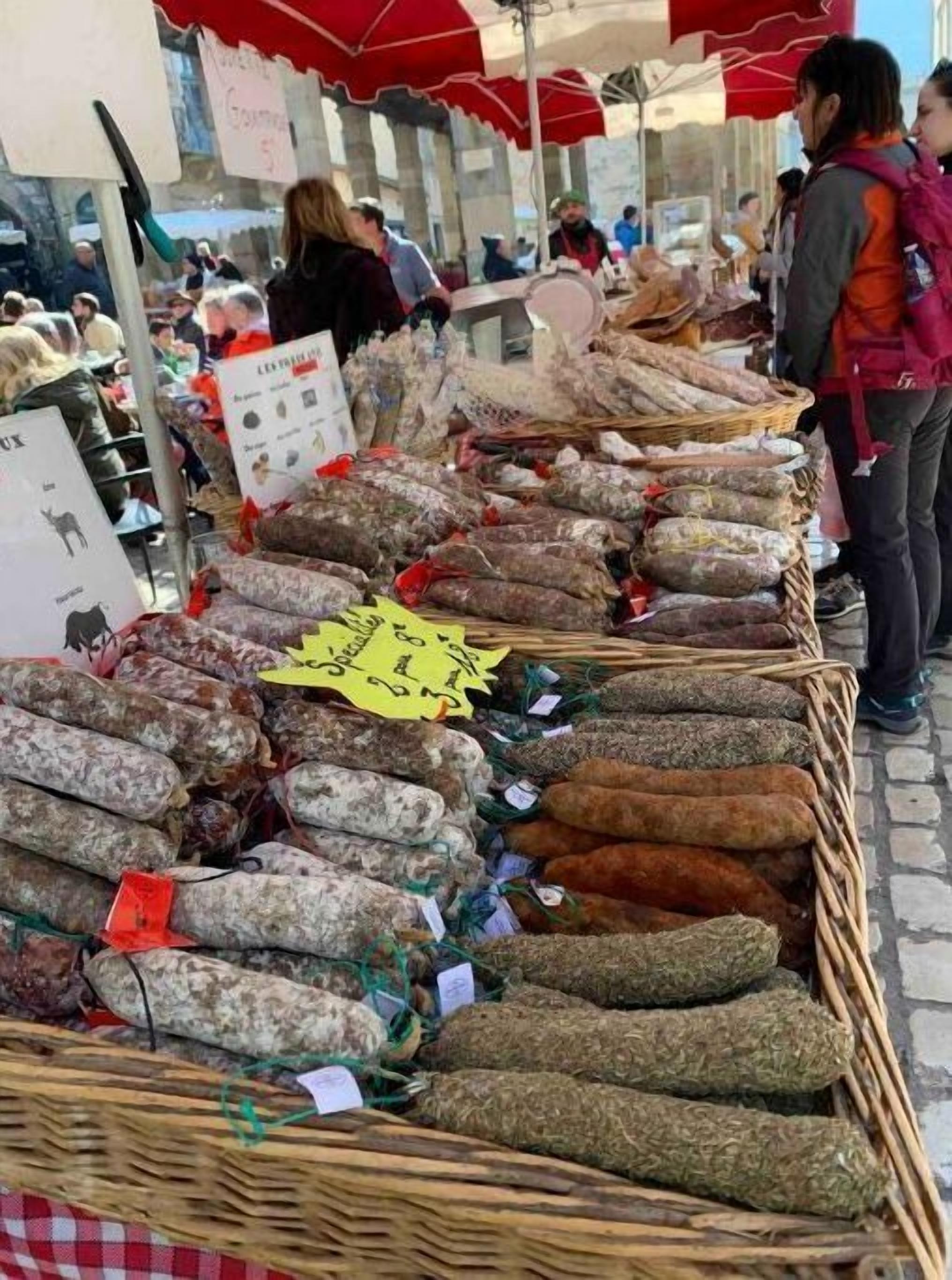Un puesto de mercado con varios tipos de salchichas exhibidas en cestas.