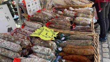 Un puesto de mercado con varios tipos de salchichas exhibidas en cestas.