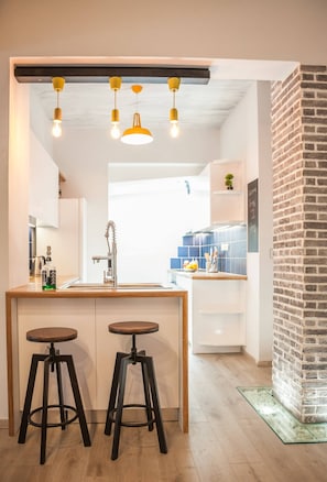 Enjoy cooking in this well-equipped kitchen with a central island, stainless steel sink, and pendant lights.