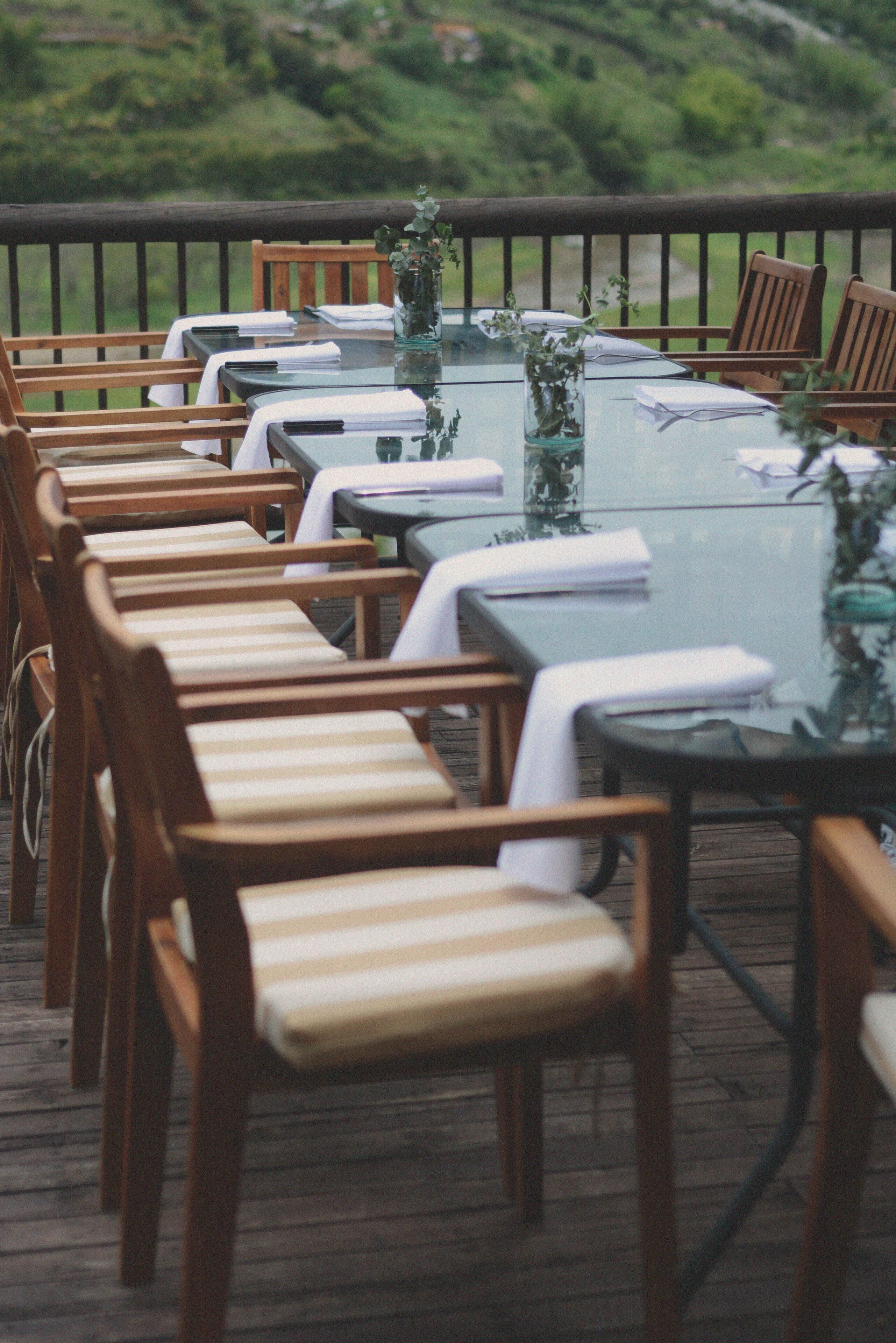 Eine Terrasse mit Holzhockern und Tischen, einige mit weißen Servietten.