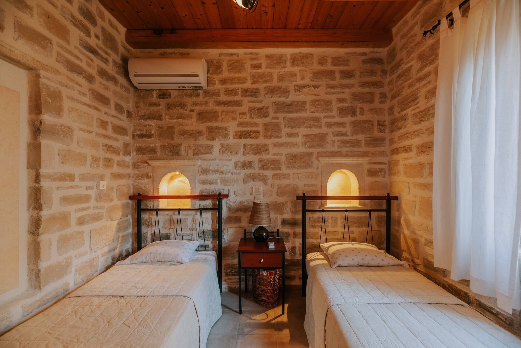 Una habitación con dos camas, una mesita y un equipo de aire acondicionado.