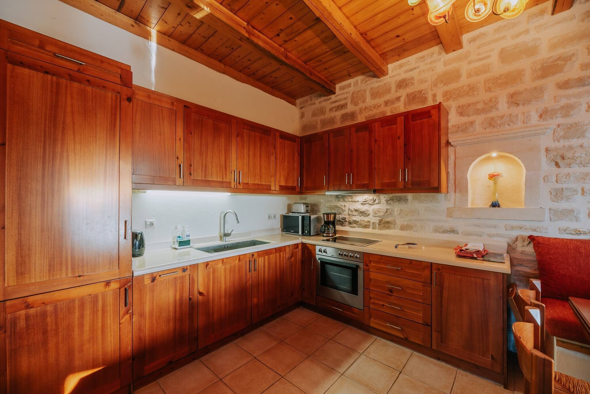 Une cuisine avec des meubles de rangement en bois, une cuisinière, un four à micro-ondes et un évier.