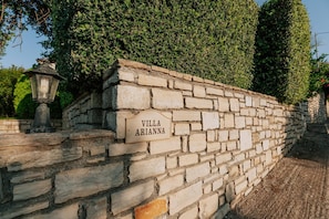 En stenmur med en skylt som visar texten ”Villa Arianna” och en lykta.