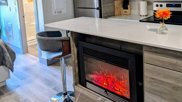 Une cuisine moderne dotée d’une cheminée intégrée, d’appareils électroménagers en acier inoxydable et d’un design minimaliste.