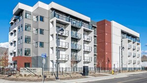 Un immeuble à plusieurs étages doté de balcons, une enseigne indiquant « Vita Resort », et un ciel d’un bleu limpide.