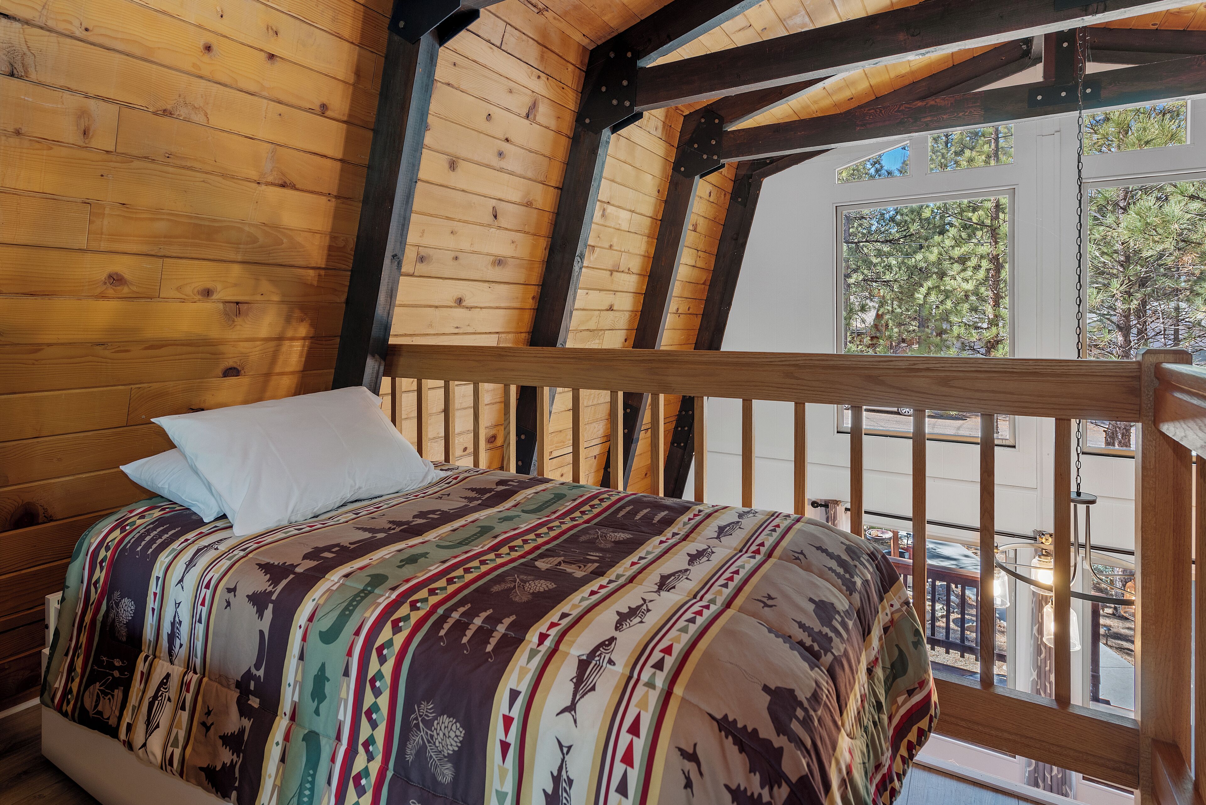 A wooden cabin bedroom with a bed, a window, and a balcony.