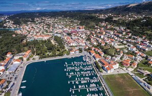 Stunning coastal town with a marina, surrounded by rolling hills and a clear sky.