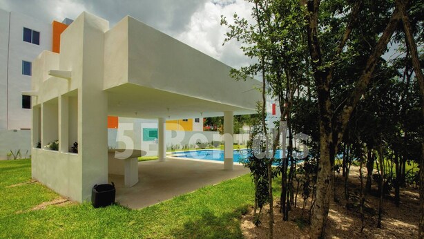 Un edificio moderno con un área exterior techada, piscina y un árbol.