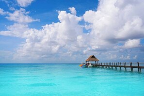 A clear blue sky, a wooden pier, and a thatched-roof structure over water. - Apartment With Pool In Playa Del Carmen (Playa del Carmen)