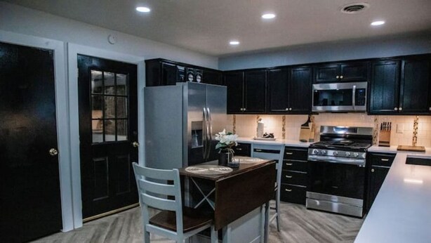 A modern kitchen with dark cabinets, stainless steel appliances, and a central island.