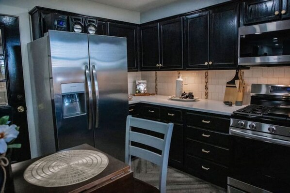 A kitchen with dark cabinets, stainless steel appliances, and a white chair.