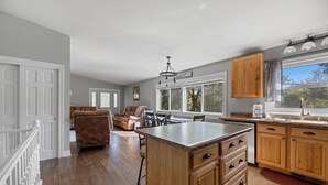 A spacious kitchen with wooden cabinets, a large island, and a view of the outdoors through the windows. - Woodburn.  (Spearfish)