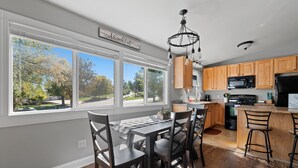 A kitchen with a dining area, large windows, and a view of a park. - Woodburn.  (Spearfish)