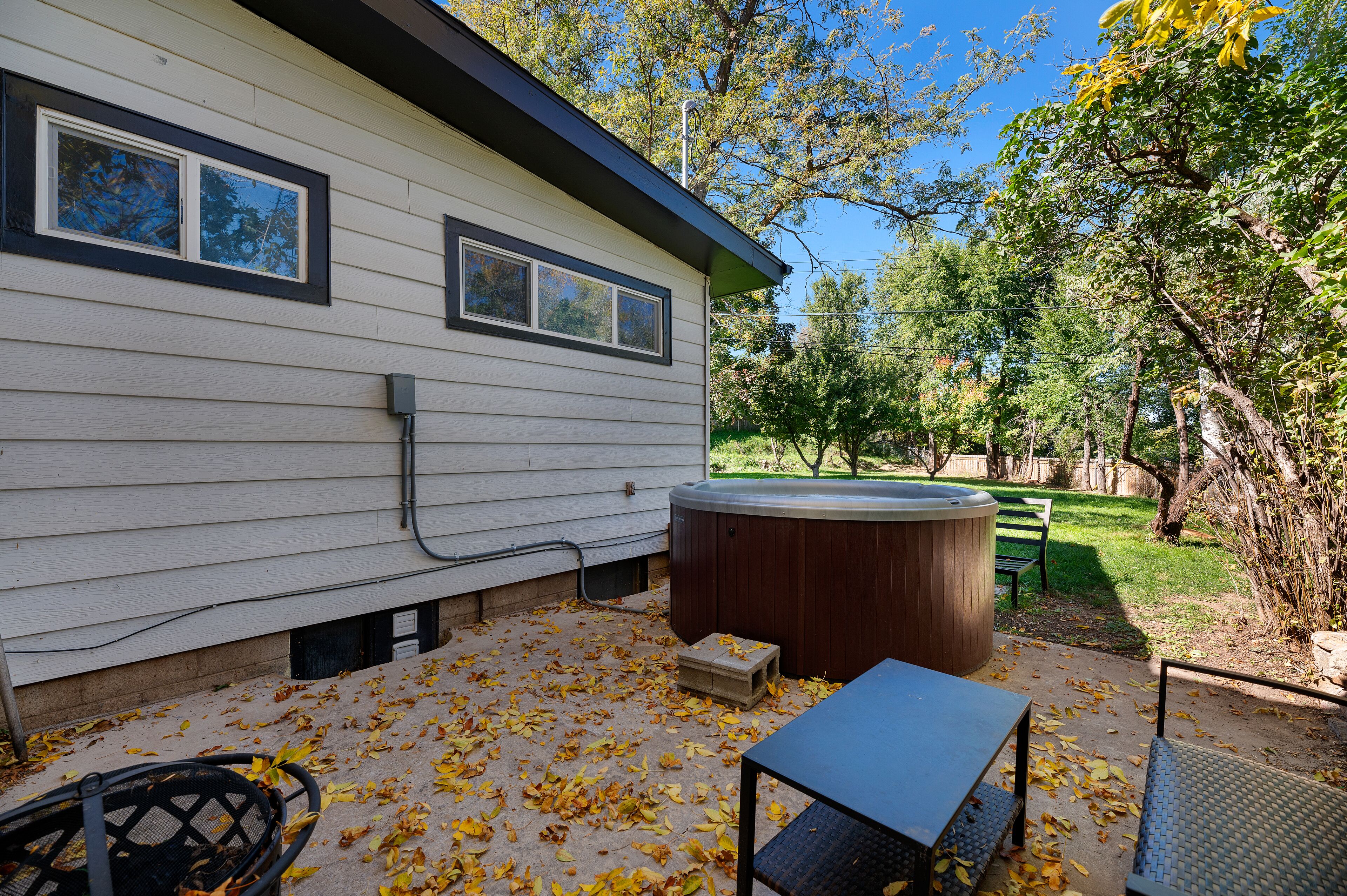 Une maison avec un jacuzzi, une table et des chaises à l’extérieur.