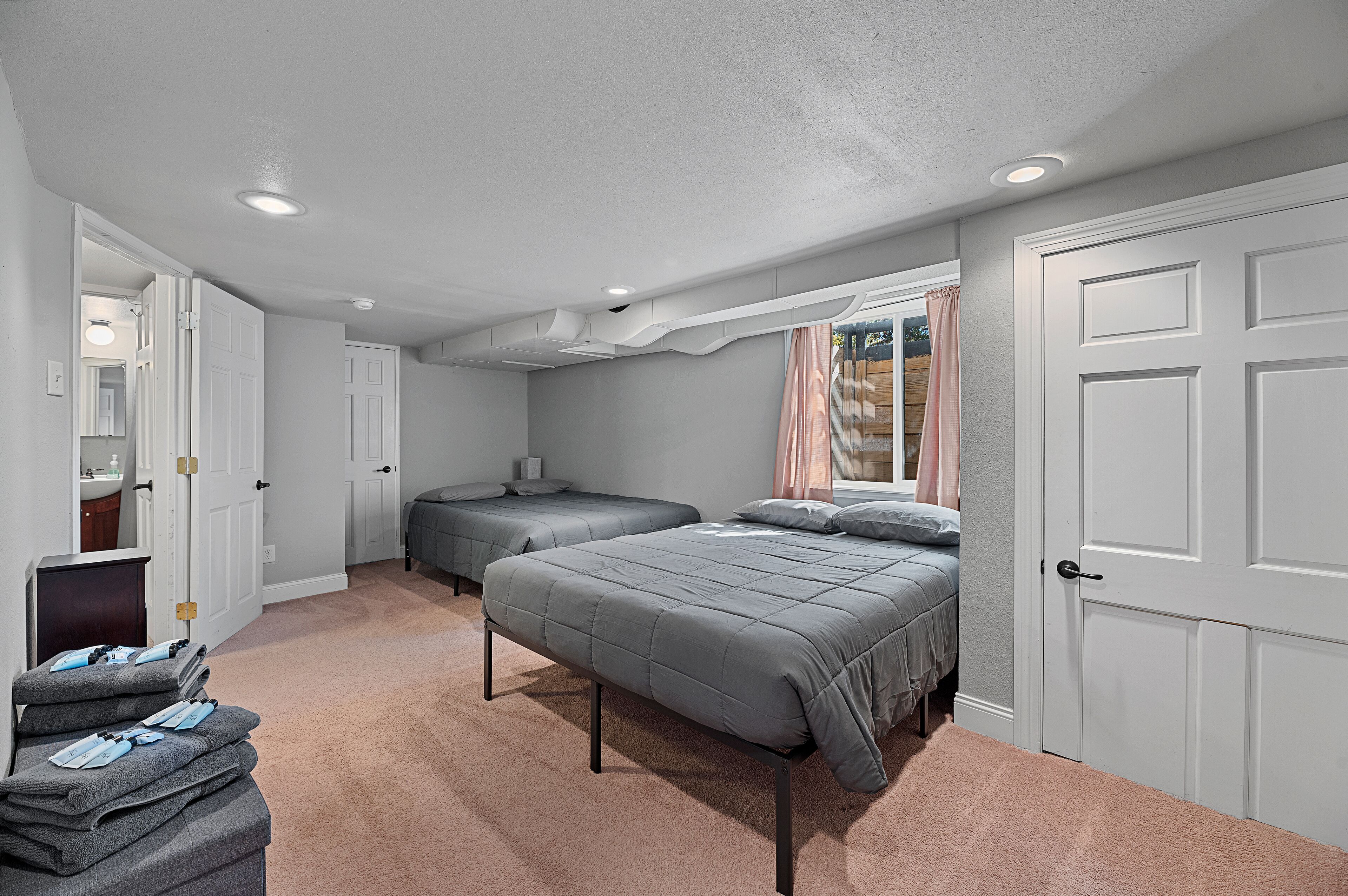 A bedroom with two beds, a desk, and a closet.