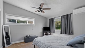 A bedroom with a bed, a ceiling fan, a TV, and a window with curtains. - Woodburn.  (Spearfish)