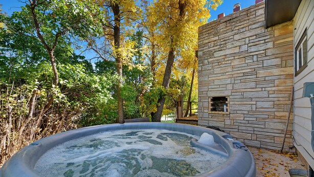 A hot tub in a backyard with stone walls and trees. - Woodburn.  (Spearfish)