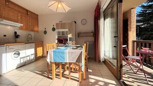A kitchen with wooden cabinets, a dining table with chairs, a microwave, and a washing machine.