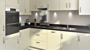 Una cocina moderna con armarios blancos, encimera negra, electrodomésticos de acero inoxidable y una cocina a gas.