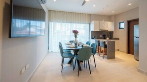 A modern dining area with a table set for four, a ceiling fan, and a kitchen area with cabinets and a refrigerator. - Kippal Onix |Luxurious 2-Bedroom Cozumel Apartment (San Miguel de Cozumel)
