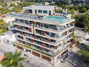 Un hôtel à plusieurs étages doté d’une piscine sur le toit, de balcons et d’une architecture moderne.