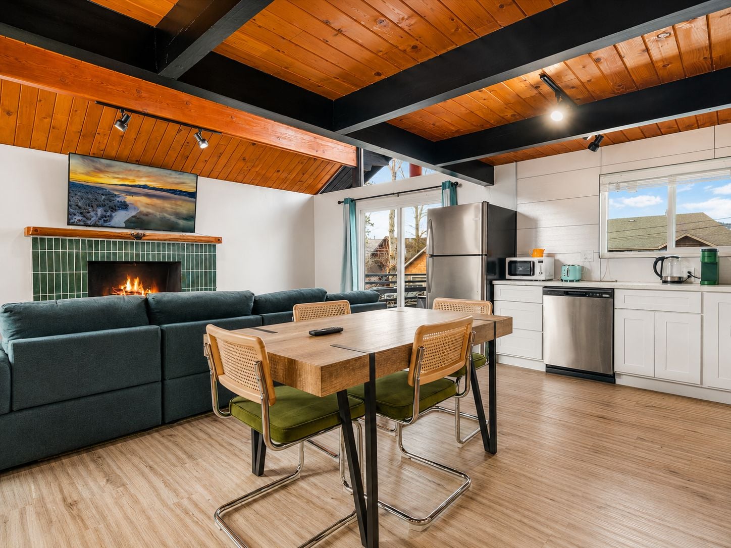 A modern kitchen with a dining area, a fireplace, and a view of the outside.