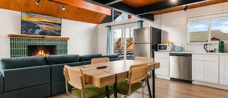 A modern kitchen with a dining area, a fireplace, and a view of the outside.