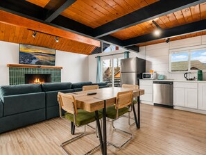 A modern kitchen with a dining area, a fireplace, and a view of the outside. - Big Bear Lake View (Big Bear Lake)