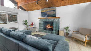 Una sala moderna con chimenea, un sofá modular y techo de madera.