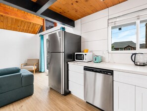 Una cocina moderna con refrigerador de acero inoxidable, microondas, tostadora y lavavajillas.