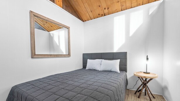 Un dormitorio con una cama, una mesita de noche, una lámpara y un espejo en la pared.