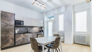 A modern kitchen with a dining table and chairs, a microwave, and a built-in oven. - Pisani Apartment Milano Repubblica (Milano)