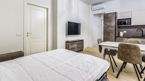A modern hotel room with a bed, a TV, a kitchenette, and a dining area. - Pisani Apartment Milano Repubblica (Milano)