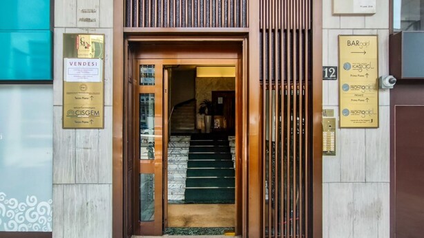 A hotel entrance with a staircase leading to a second floor, a sign for 'VENDESI,' and a 'BARgold' sign indicating a bar. - Pisani Apartment Milano Repubblica (Milano)