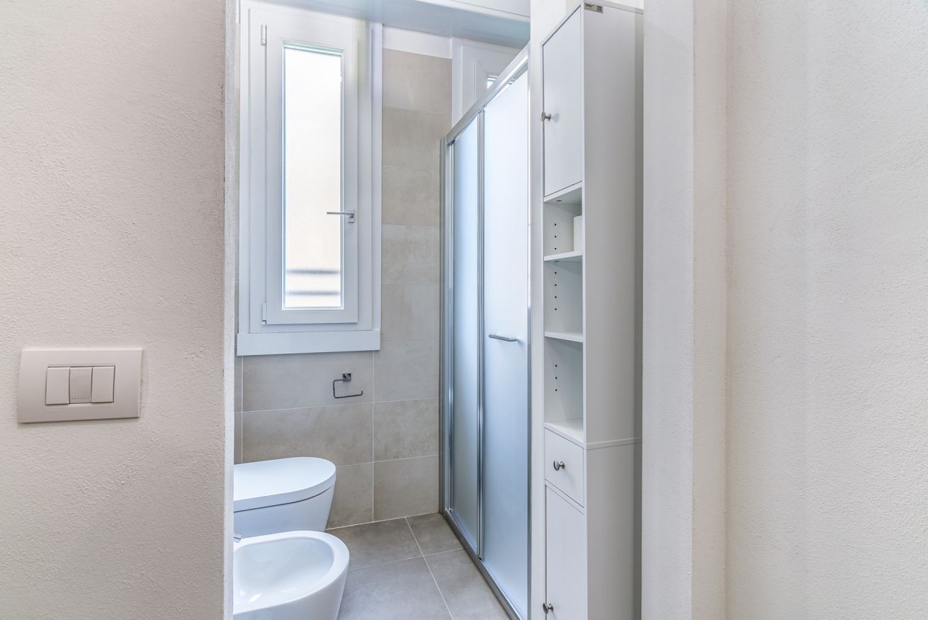 A bathroom with a toilet, a shower, and a cabinet.