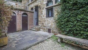 A stone building with arched doors and windows, a gravel pathway, and a bench. - Gelsomino - Sweet Dreams in Florence (Firenze)