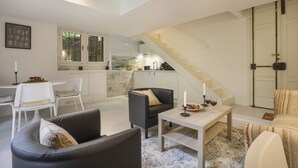 A modern living room with a sofa, a coffee table, and a dining area with chairs. A staircase leads to a loft space. - Gelsomino - Sweet Dreams in Florence (Firenze)