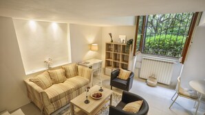 A living room with a sofa, armchair, coffee table, and a bookshelf. - Gelsomino - Sweet Dreams in Florence (Firenze)