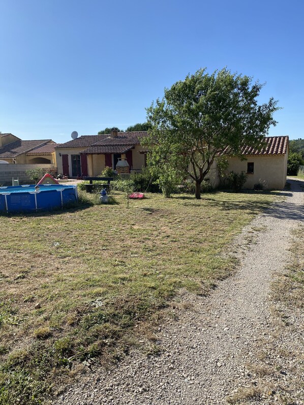 Un quartier résidentiel avec une maison, une piscine et un arbre.