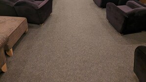 Une salle de cinéma avec des rangées de sièges violets, un sol recouvert de moquette et un grand écran à l’avant.