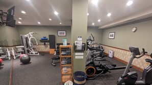 Une salle de sport équipée de divers appareils d’exercice, notamment des tapis de course, des vélos d’appartement et des poids.