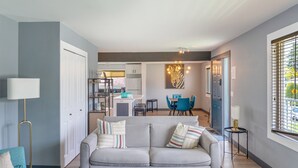 Een moderne woonkamer met een grijze bank, een salontafel en een eethoek op de achtergrond.