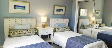 A hotel room with two beds, a nightstand with a lamp, and a mirror.